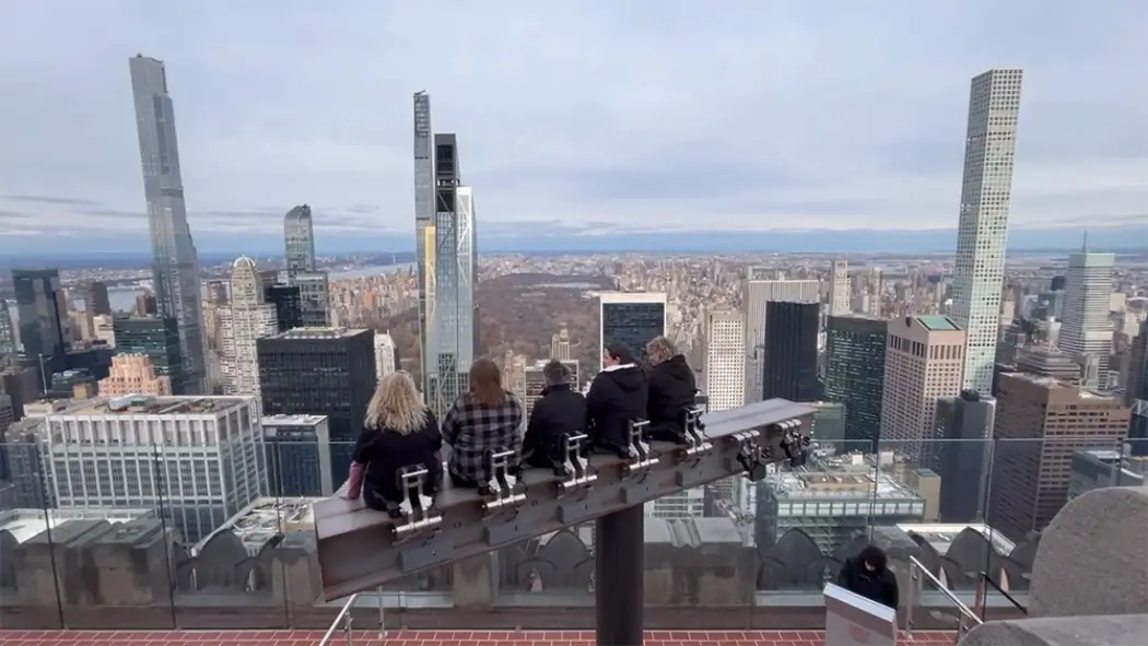 People enjoying the Beam at Top of the Rock with Central Park and Manhattan skyscrapers in view