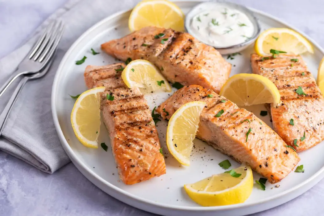 Grilled salmon fillets with lemon wedges at One Dine